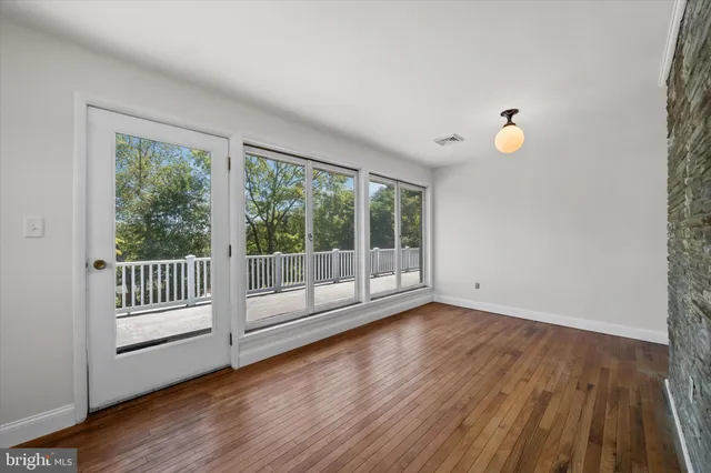a view of an empty room with wooden floor and a kitchen