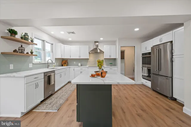 a kitchen with stainless steel appliances granite countertop a refrigerator a stove and a wooden floors