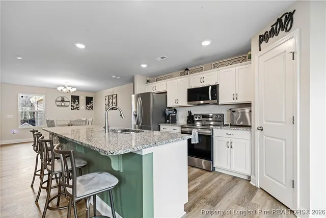 a kitchen with granite countertop a refrigerator a sink and white cabinets