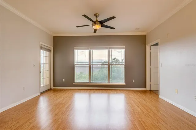 a view of an empty room with wooden floor and a window