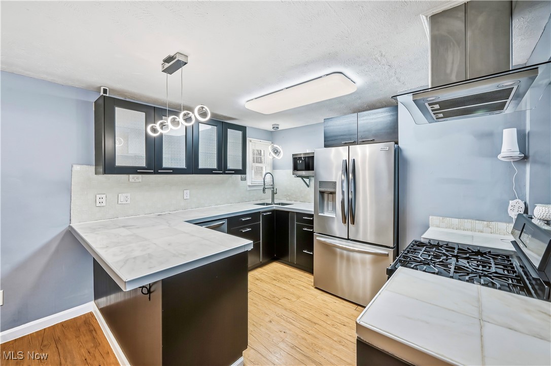 245 North Road Niles, OH 44446 - Photo 14 of 45 Kitchen with island range hood, a kitchen breakfast bar, stainless steel appliances, light countertops, and a peninsula