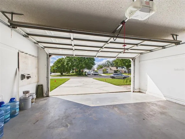 a view of a white house next to a yard with big trees