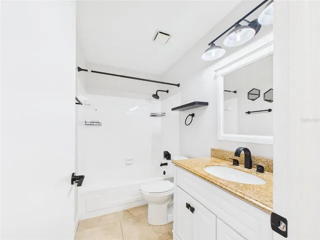a bathroom with a granite countertop sink a toilet and shower