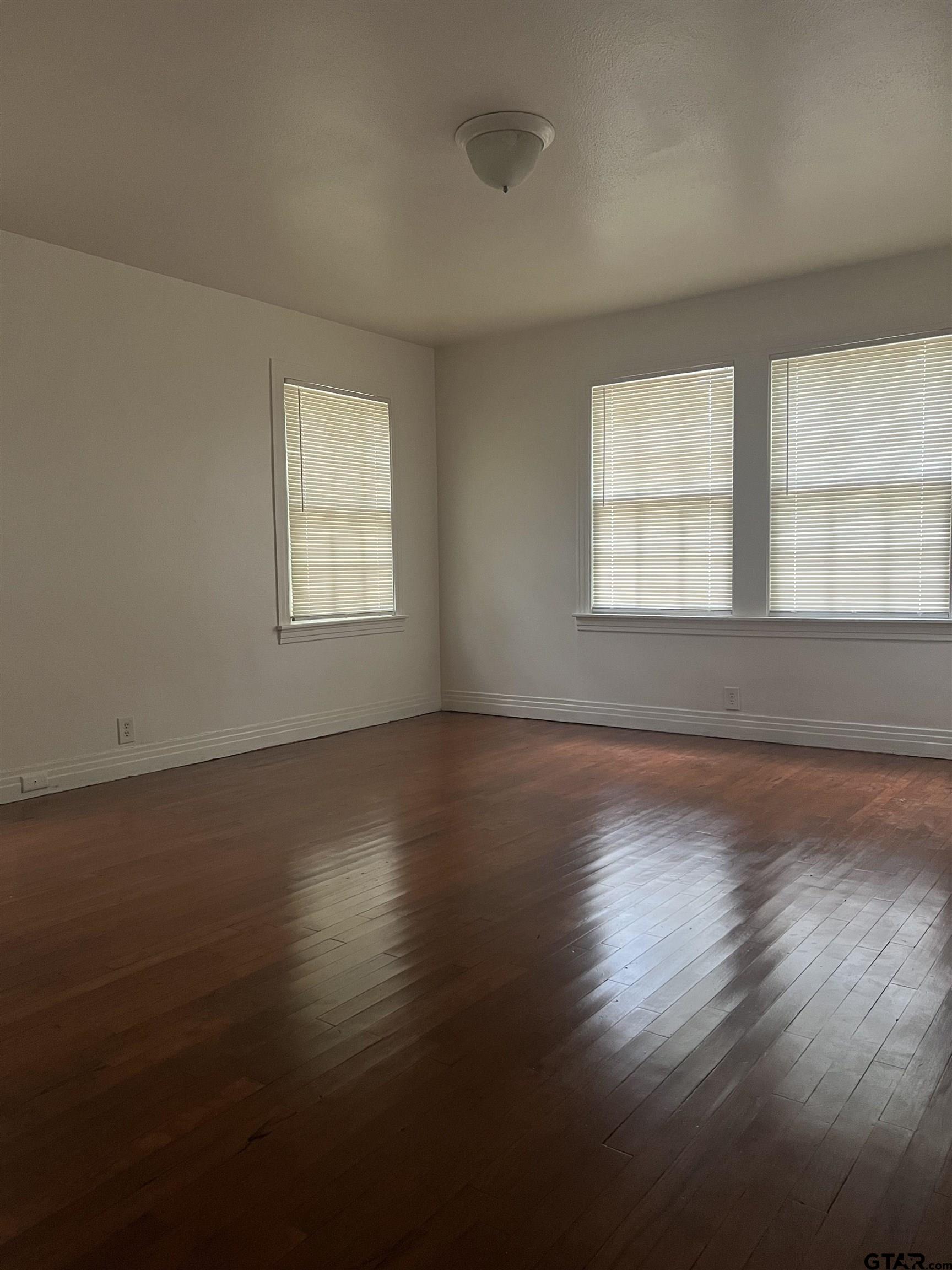 902 West 5th Street Tyler, TX 75701 - Photo 7 of 11 an empty room with wooden floor and windows