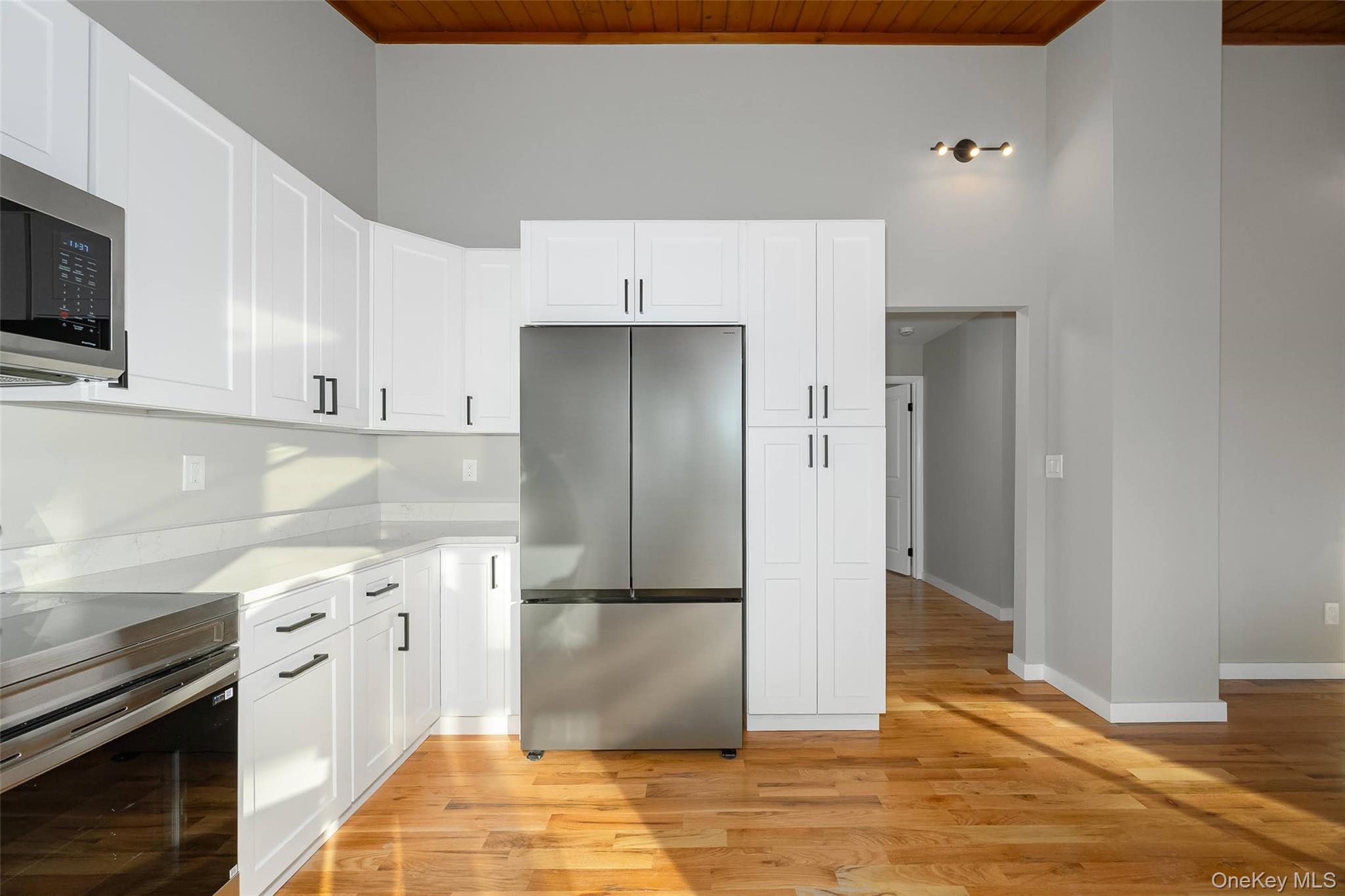 261 Freedom Road Pleasant Valley, NY 12569 - Photo 9 of 50 Kitchen featuring stainless steel appliances, white cabinetry, wood ceiling, light wood-type flooring, and light stone countertops