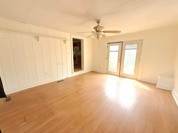 a view of an empty room with a window and wooden floor