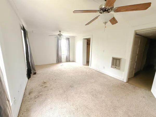 a view of a big room with a ceiling fan and a window