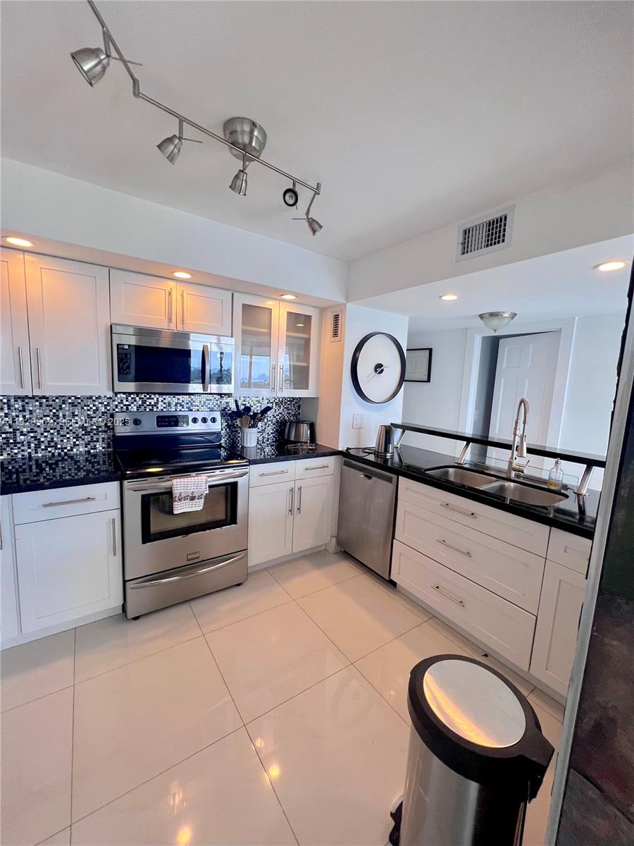5838 Collins Avenue, Unit 8B Miami Beach, FL 33140 - Photo 11 of 30 a kitchen with stainless steel appliances granite countertop a sink and cabinets