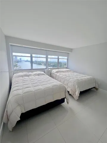 a bedroom with two bed and a large window