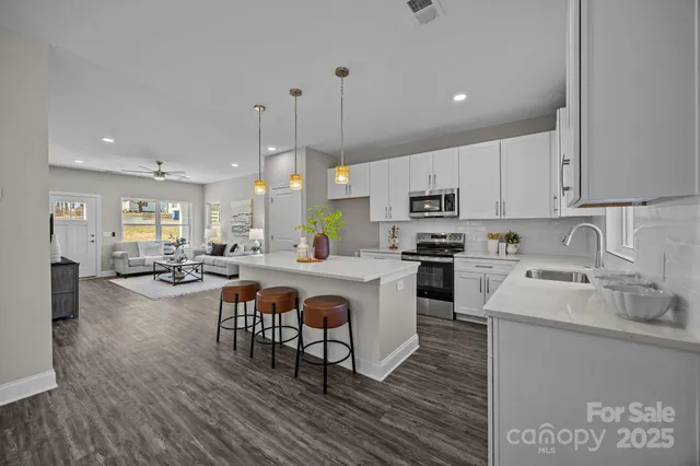 a kitchen with stove a sink and white cabinets with wooden floor
