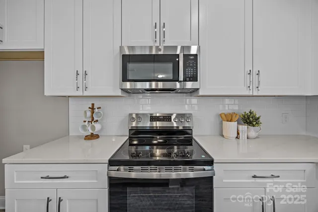 a kitchen with stainless steel appliances granite countertop a stove and a white cabinets