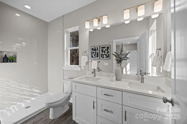 a bathroom with a toilet a double vanity sink and a mirror