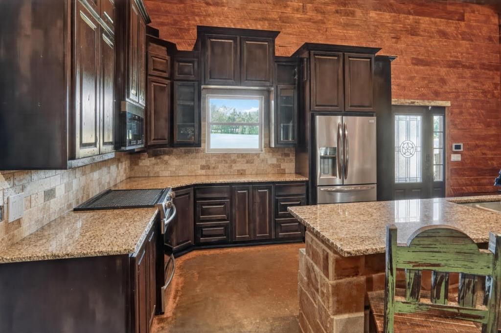 1524 County Road Sumner, TX 75486 - Photo 14 of 35 a kitchen with granite countertop a oven a refrigerator and wooden cabinets