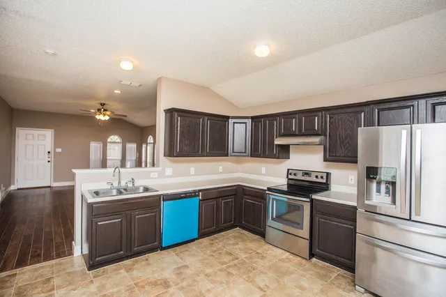 a kitchen with stainless steel appliances granite countertop a sink stove and refrigerator