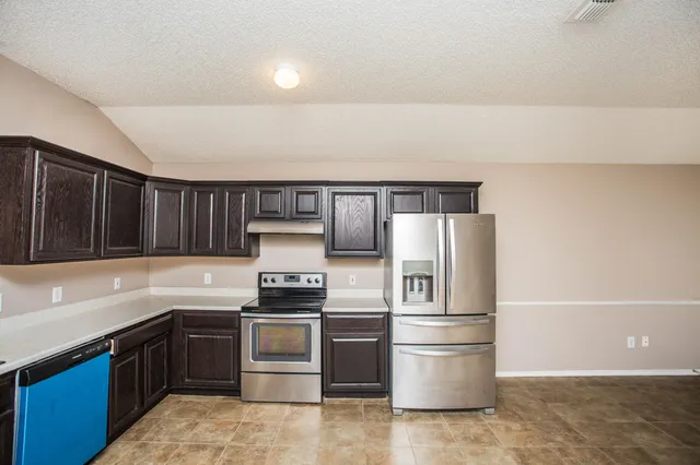 a kitchen with a stove top oven and refrigerator