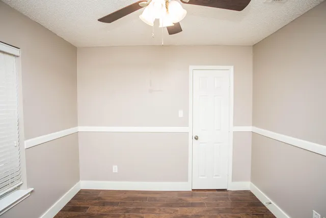 an empty room with wooden floor and fan