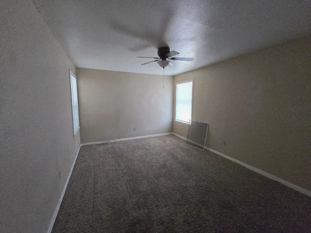 an empty room with windows and fan