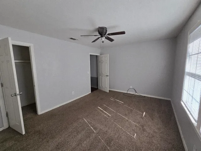 an empty room with windows and fan