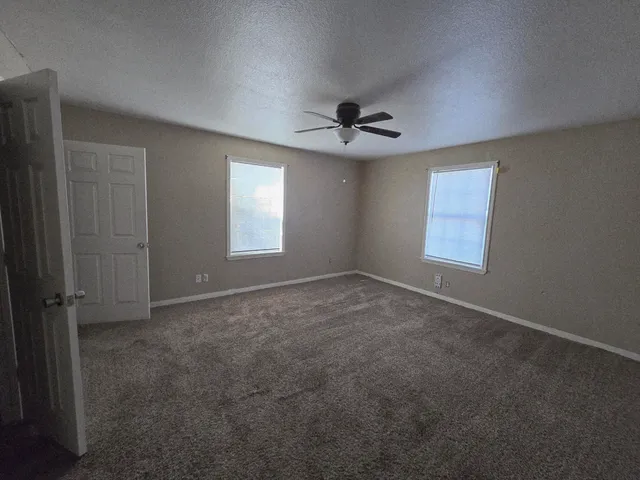 an empty room with windows and fan