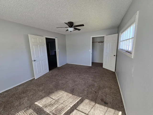 a view of a big room with windows and chandelier fan