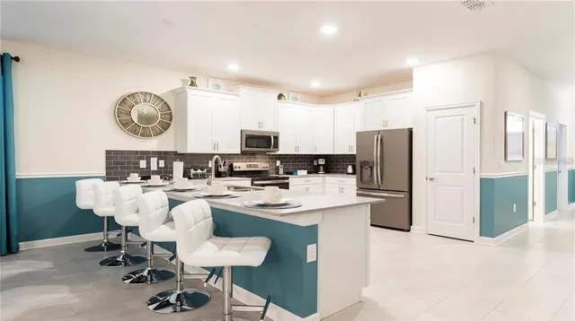 a kitchen with a refrigerator a stove a sink and chairs