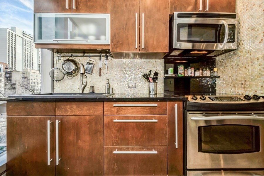 1300 North Astor Street, Unit 6B Chicago, IL 60610 - Photo 6 of 10 a kitchen with stainless steel appliances granite countertop a stove and a microwave