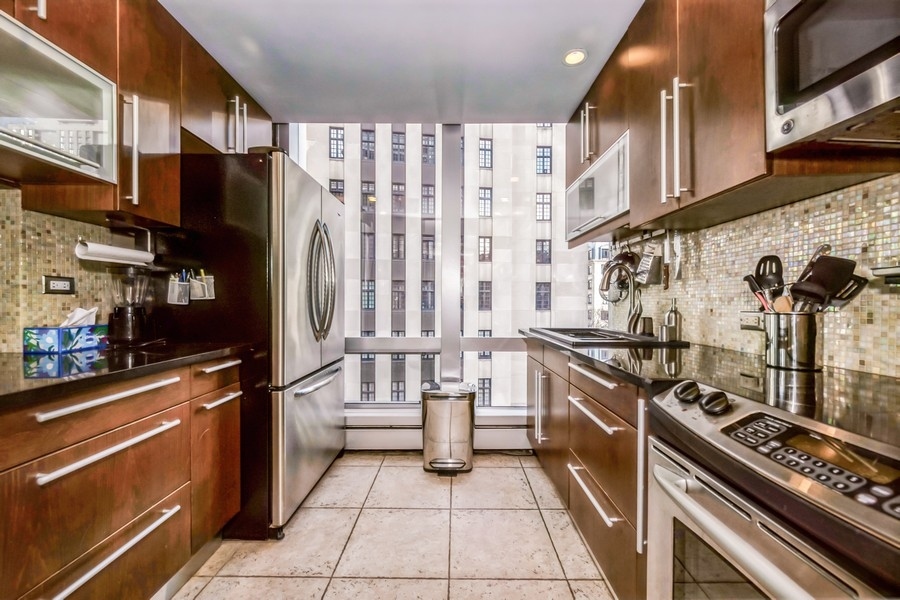 1300 North Astor Street, Unit 6B Chicago, IL 60610 - Photo 7 of 10 a kitchen with stainless steel appliances granite countertop a stove and a refrigerator