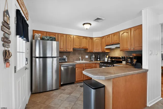 a kitchen with stainless steel appliances granite countertop a refrigerator a sink a stove a microwave and island