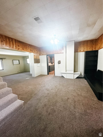 393 Old Mill Road Glenwood, UT 84730 - Photo 4 of 10 Carpeted living area featuring wood paneling, a chandelier light fixture, and built-in shelving