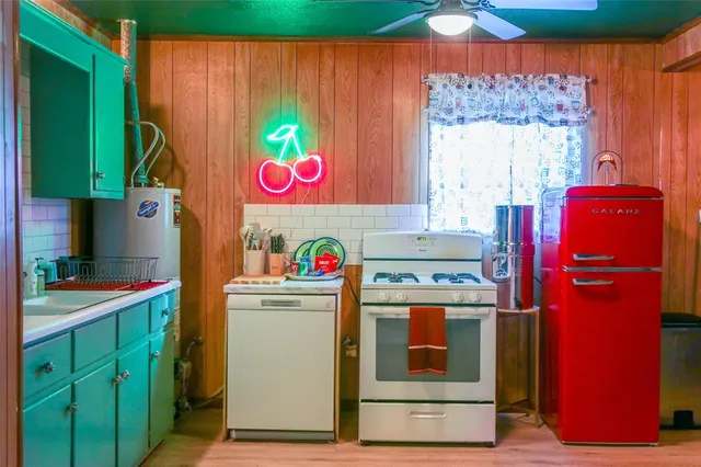a utility room with fridge and wooden floor
