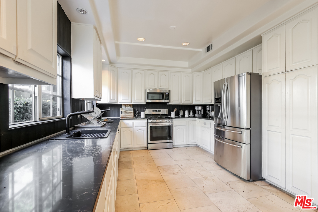 1643 Buckingham Road Los Angeles, CA 90019 - Photo 5 of 26 a kitchen with stainless steel appliances granite countertop a refrigerator a stove a sink a washer and dryer with wooden floor