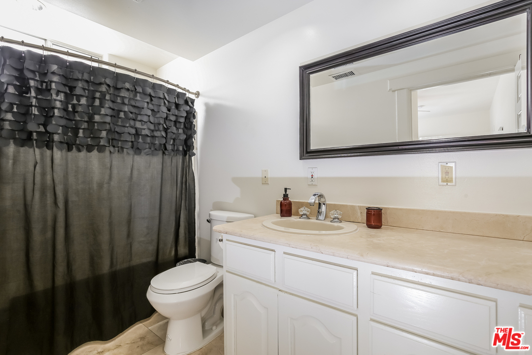 1643 Buckingham Road Los Angeles, CA 90019 - Photo 8 of 26 a bathroom with a toilet a sink a vanity and mirror