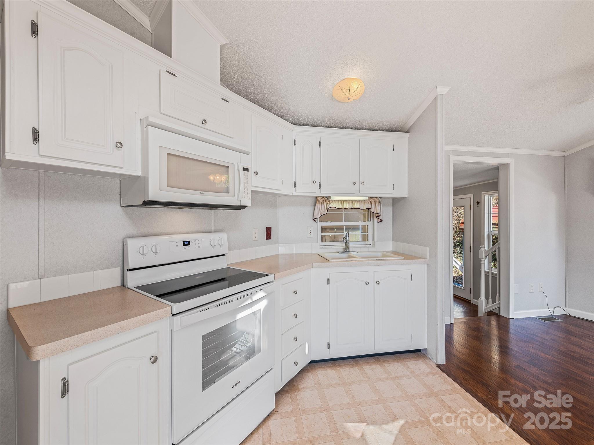 93 Merry Way Clyde, NC 28721 - Photo 12 of 24 a kitchen with cabinets stainless steel appliances and wooden floor