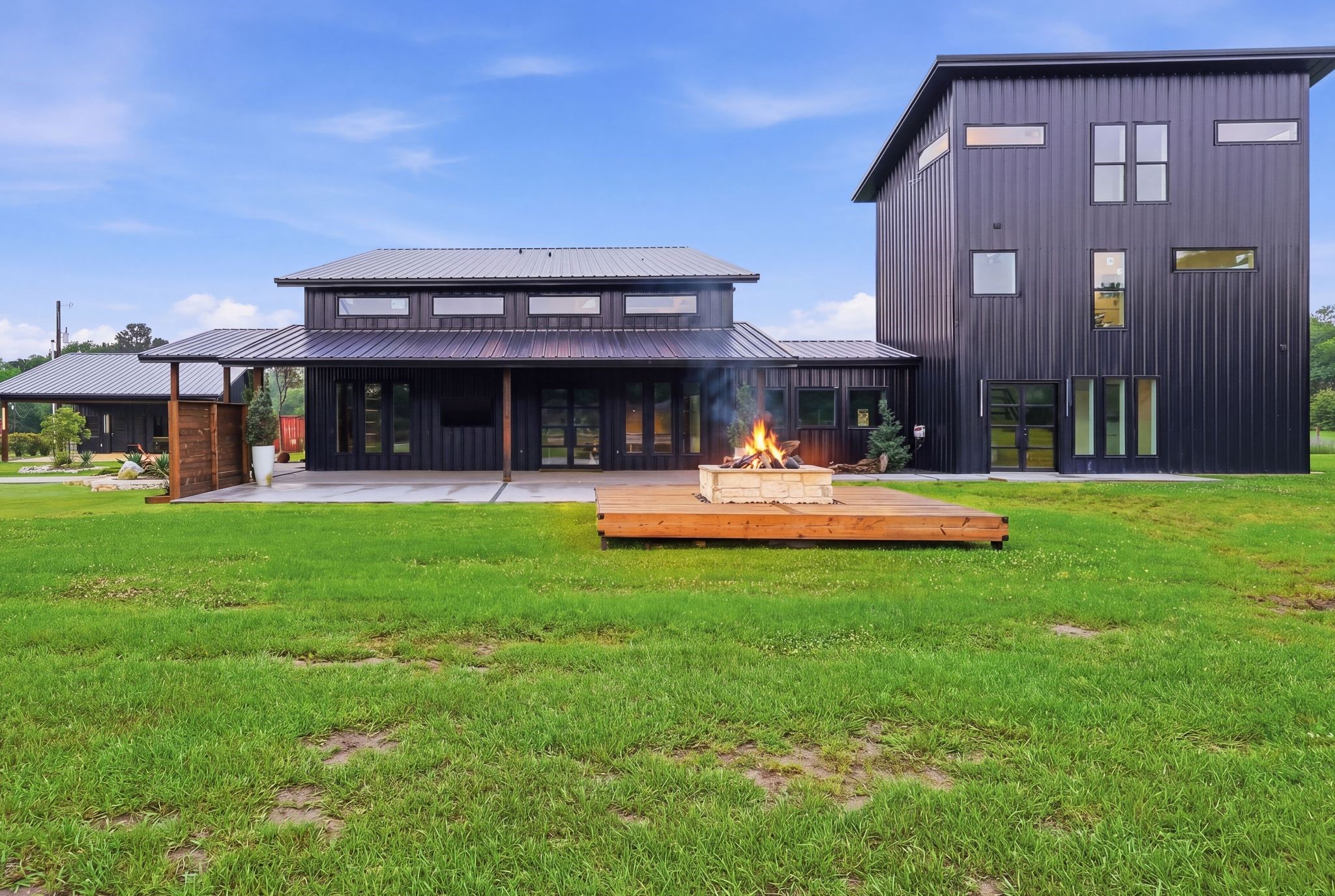 2743 Bobville Road Montgomery, TX 77316 - Photo 47 of 50 This modern home features a sleek black exterior with large windows for natural light. It includes a spacious backyard with a wooden deck and a cozy fire pit, perfect for outdoor gatherings.
