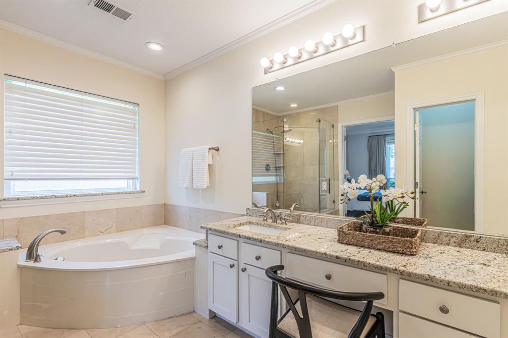300 Sundance Circle Irving, TX 75063 - Photo 13 of 39 Spacious bathroom featuring a built-in corner soaking tub, a dual vanity with granite countertops, and a glass-enclosed shower with tiled walls