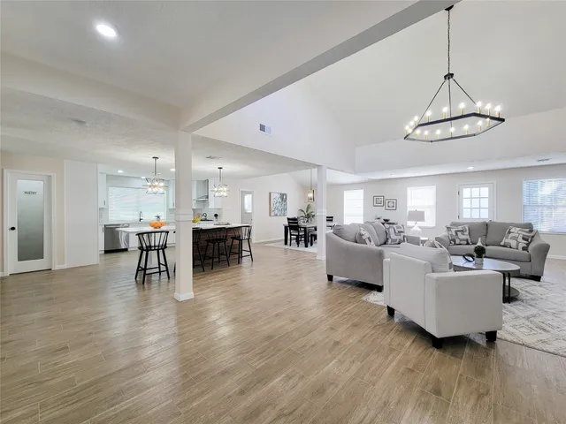 a living room with furniture dining table a window and kitchen view