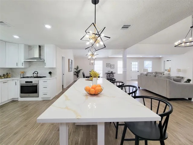 a kitchen with stainless steel appliances granite countertop a dining table chairs and white cabinets