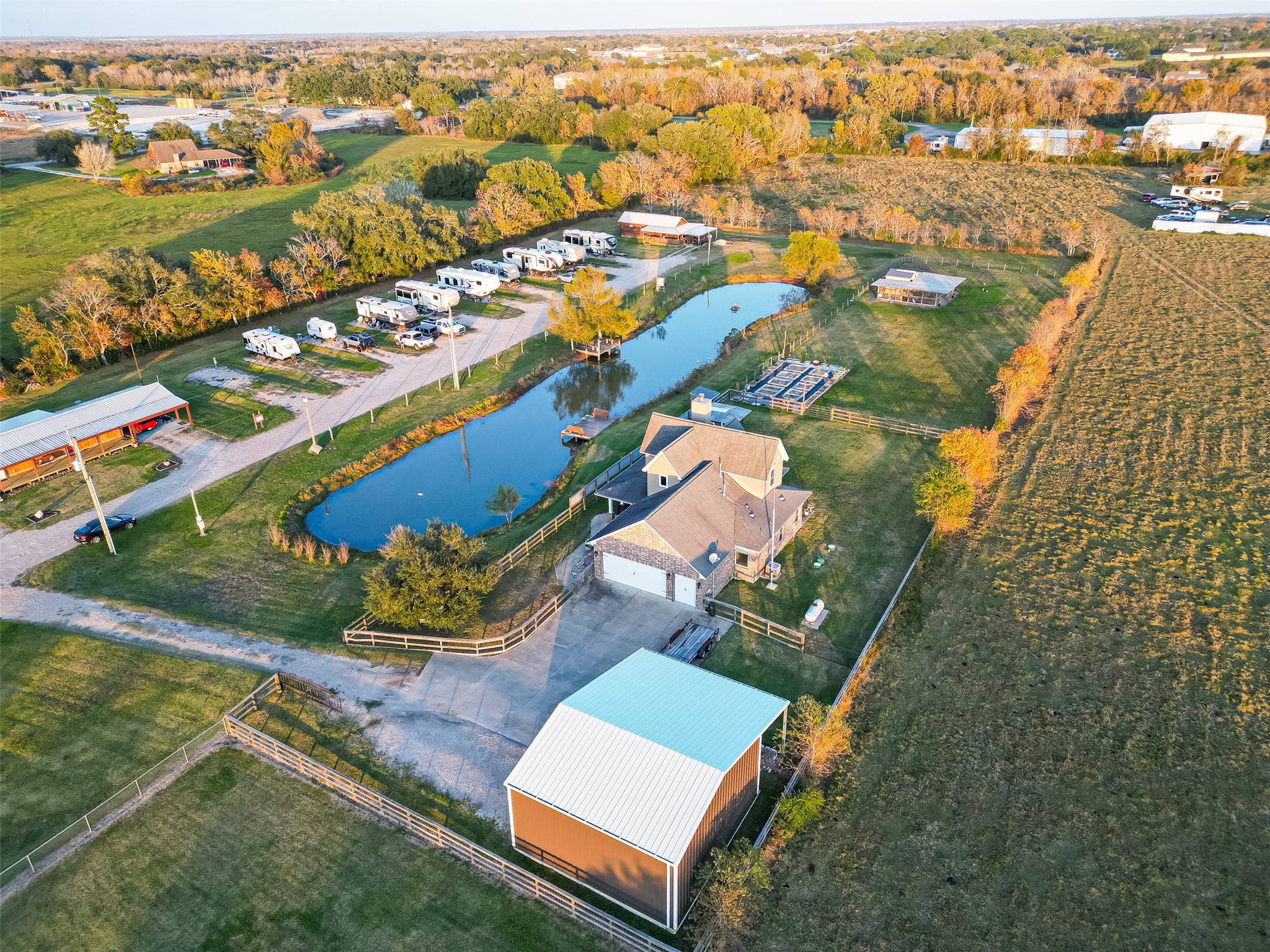 912 County Road 340 Angleton, TX 77515 - Photo 45 of 50 This aerial view showcases a spacious rural property featuring a charming house, a large pond, and ample green space. The property includes a barn and is surrounded by open fields, offering a peaceful and private setting.