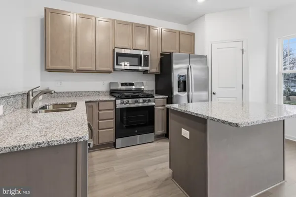 a kitchen with granite countertop a refrigerator stove and sink