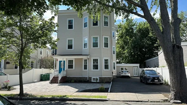 a view of a white house with large windows next to a road
