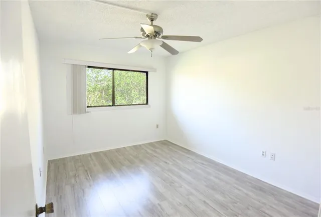 an empty room with a window and a ceiling fan