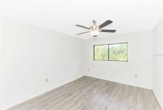 an empty room with wooden floor and ceiling fan