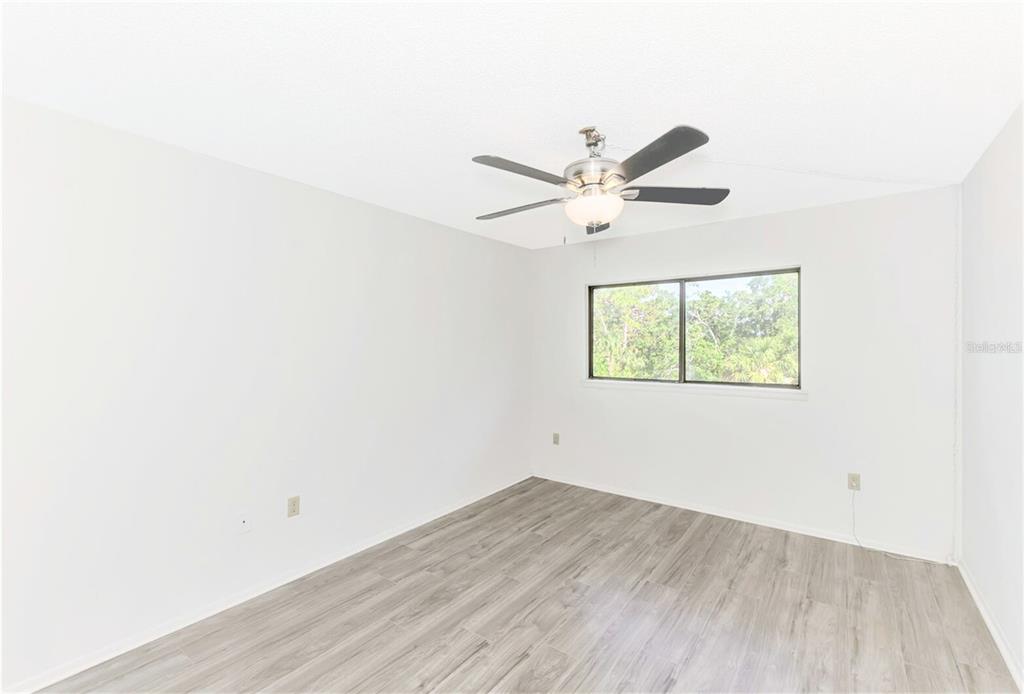 935 Sunridge Way, Unit B4 Sarasota, FL 34234 - Photo 30 of 45 an empty room with wooden floor and ceiling fan