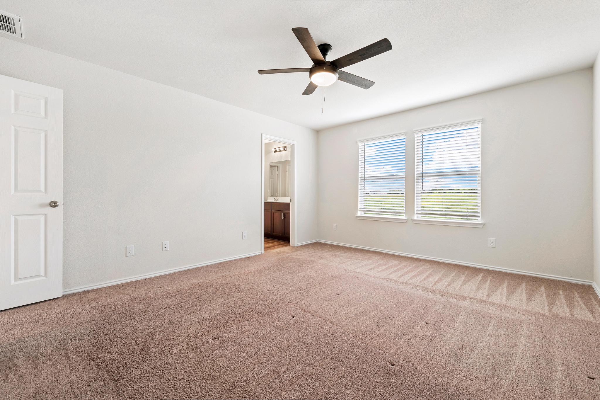 217 Innisfree Road Jarrell, TX 76537 - Photo 22 of 39 A spacious primary bedroom with a ceiling fan offers comfort and direct access to a private bath.