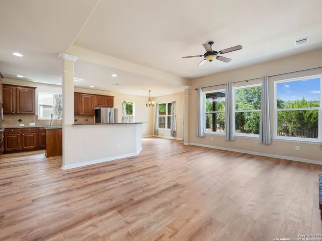 a view of a kitchen with furniture a ceiling fan and wooden floor