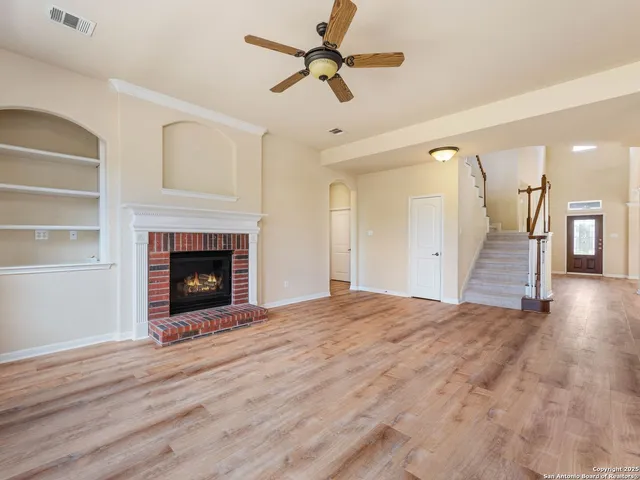 a view of empty room with wooden floor and a fireplace