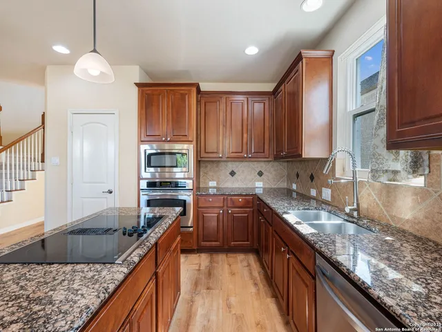 a kitchen with kitchen island granite countertop a sink counter top space appliances and cabinets
