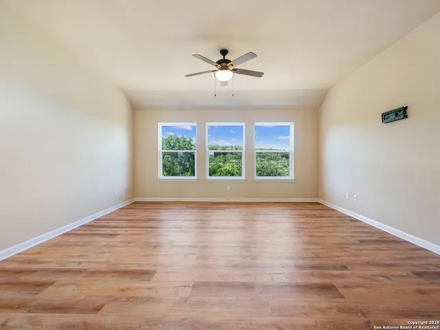 a view of empty room with wooden floor and fan
