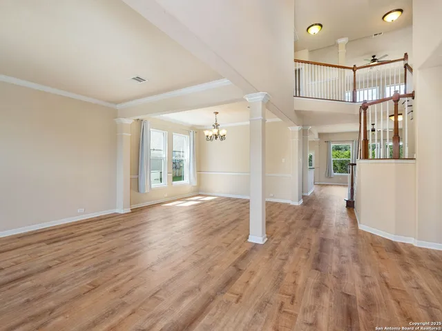 a view of an empty room with wooden floor and windows