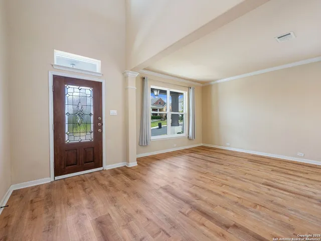 a view of an empty room with wooden floor and a window